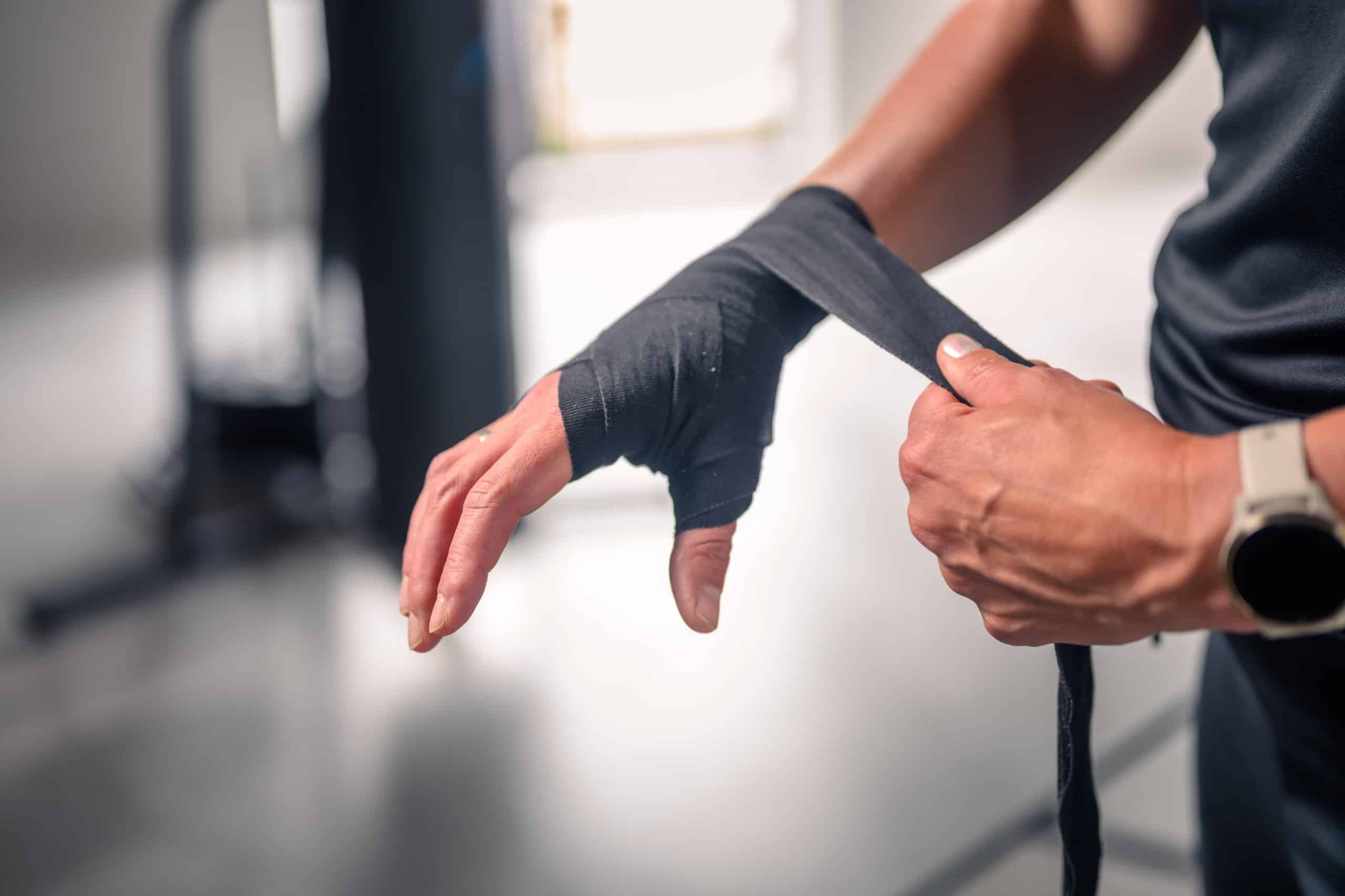 Close-up van een hand die een zwarte boksbandage om de pols wikkelt
