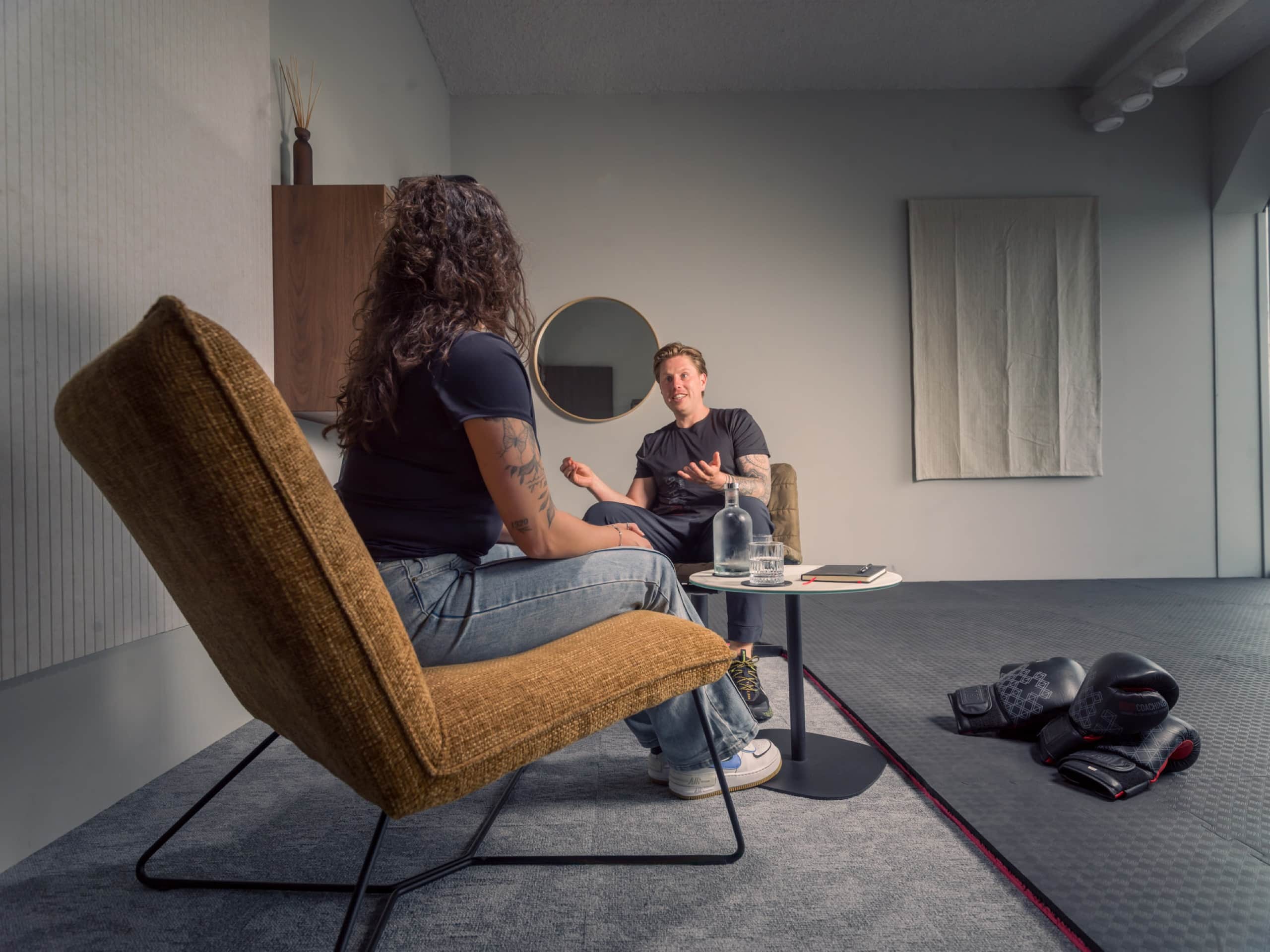 Cliënt in een fauteuil in gesprek met een coach in een rustige coachruimte