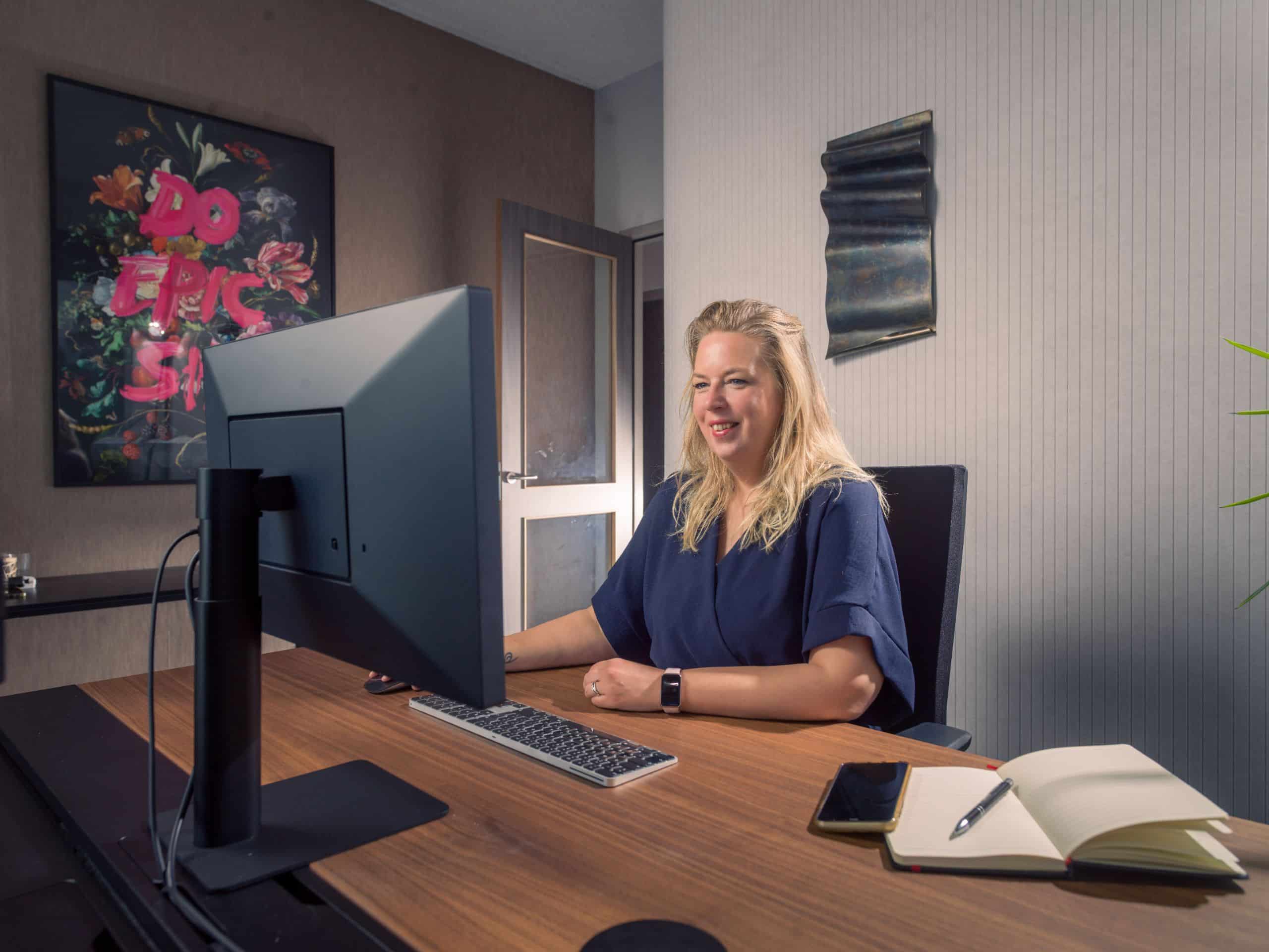 Vrouw werkt aan een bureau achter een computerscherm