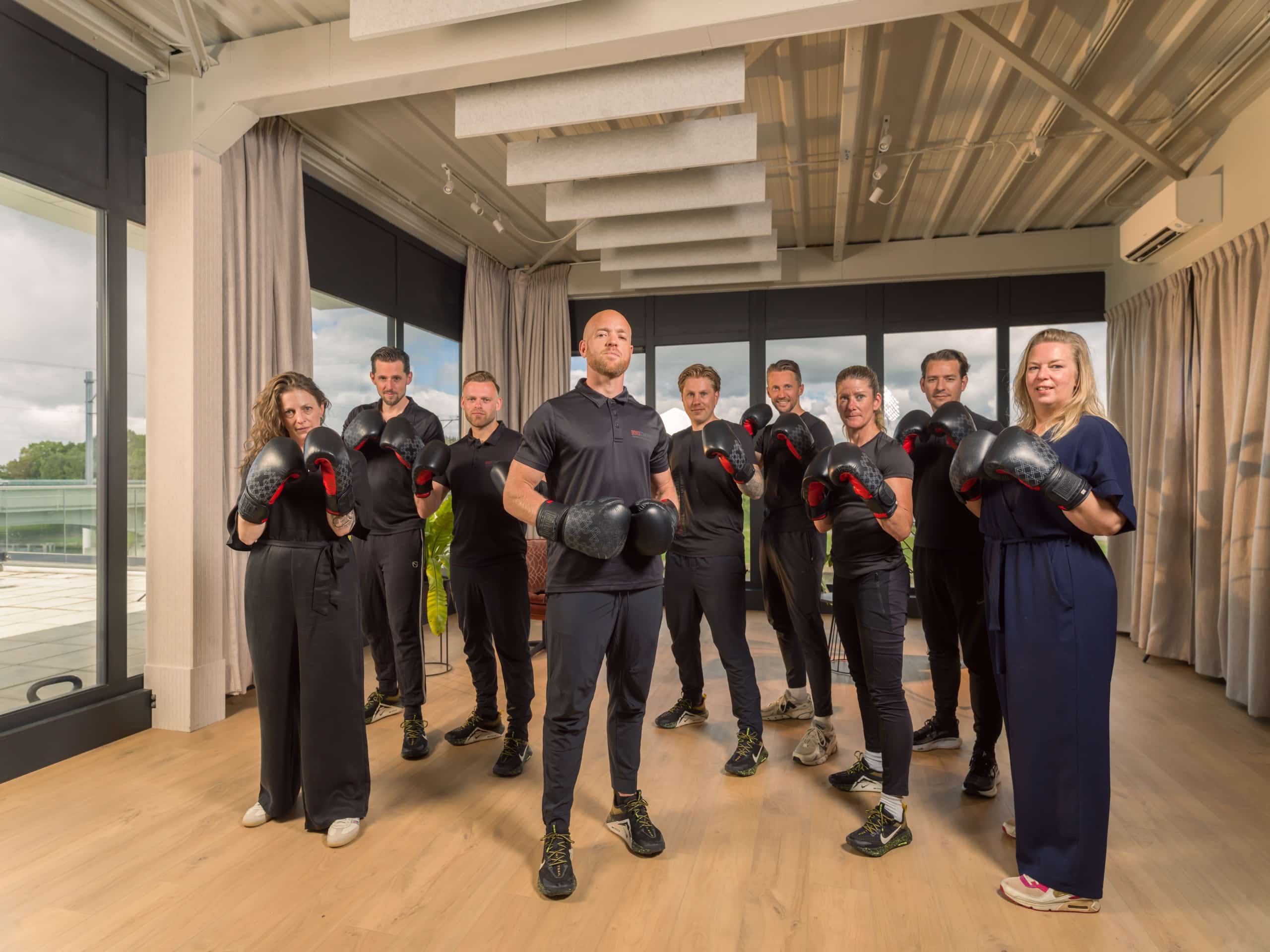 Het team van bokscoaches van Bokscoaching staat met bokshandschoenen in een lichte trainingsstudio