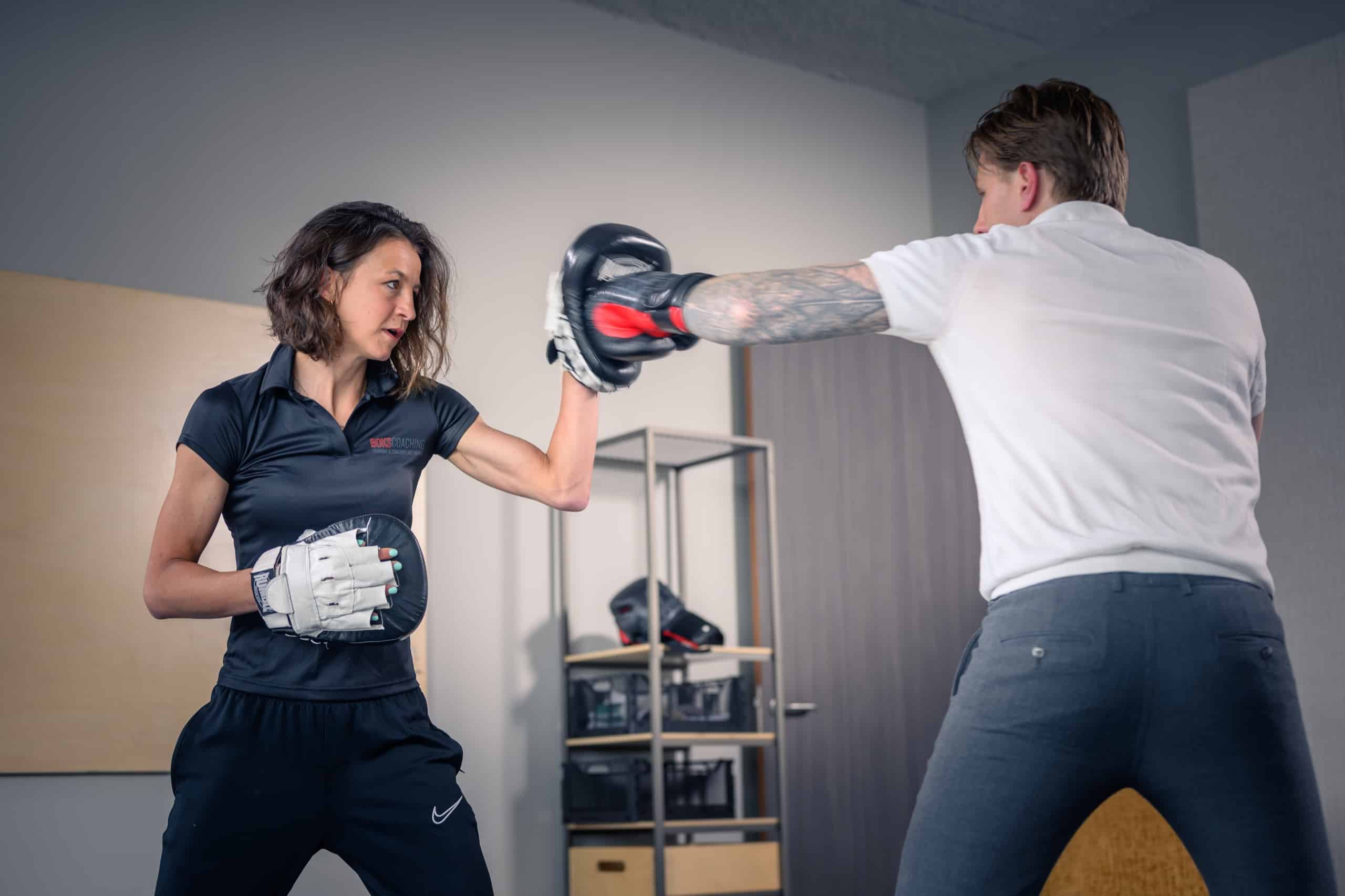 Coach vangt met handpads stoten op van een deelnemer met bokshandschoenen