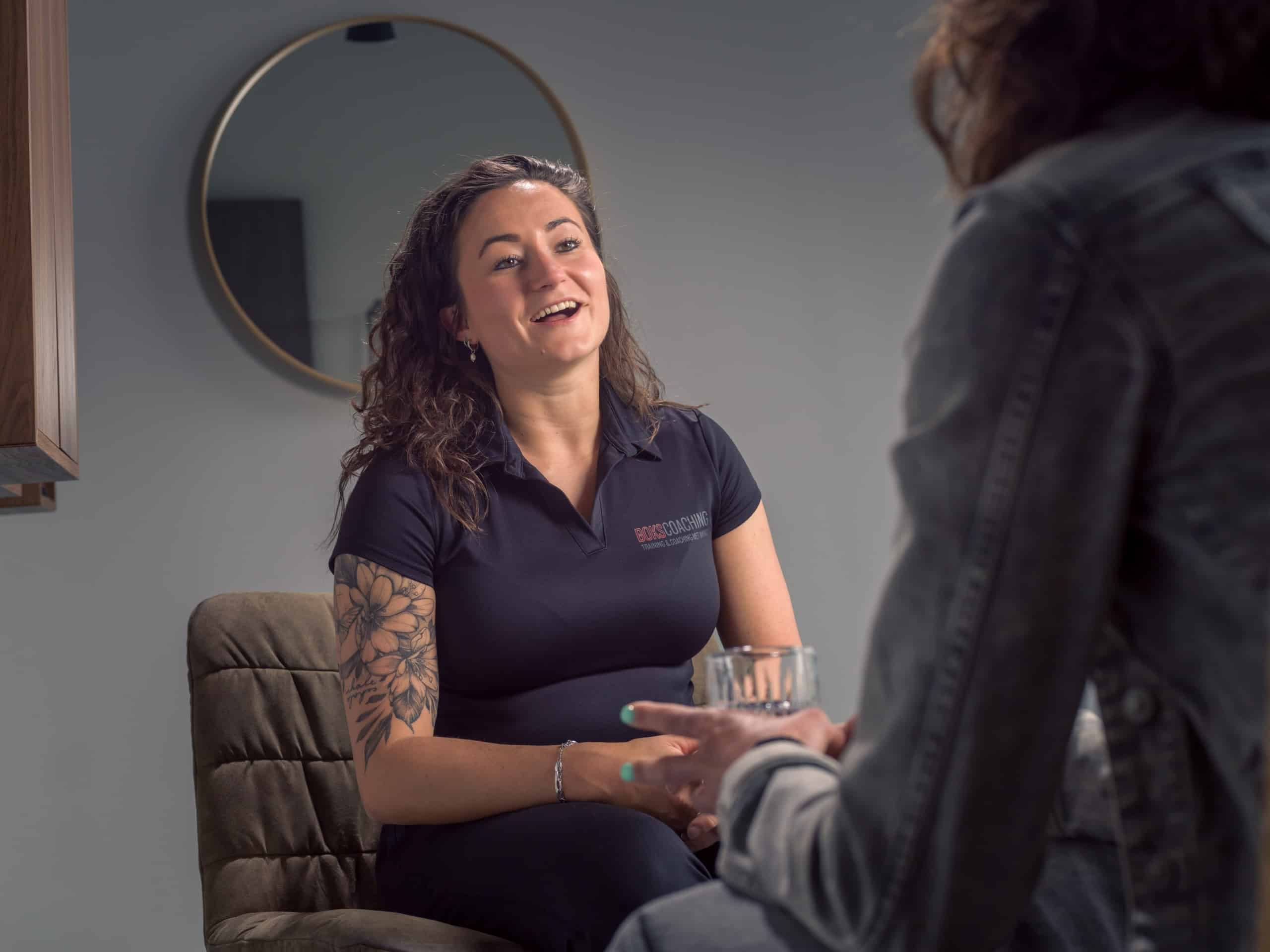 Coach in gesprek met een cliënt, lachend en betrokken