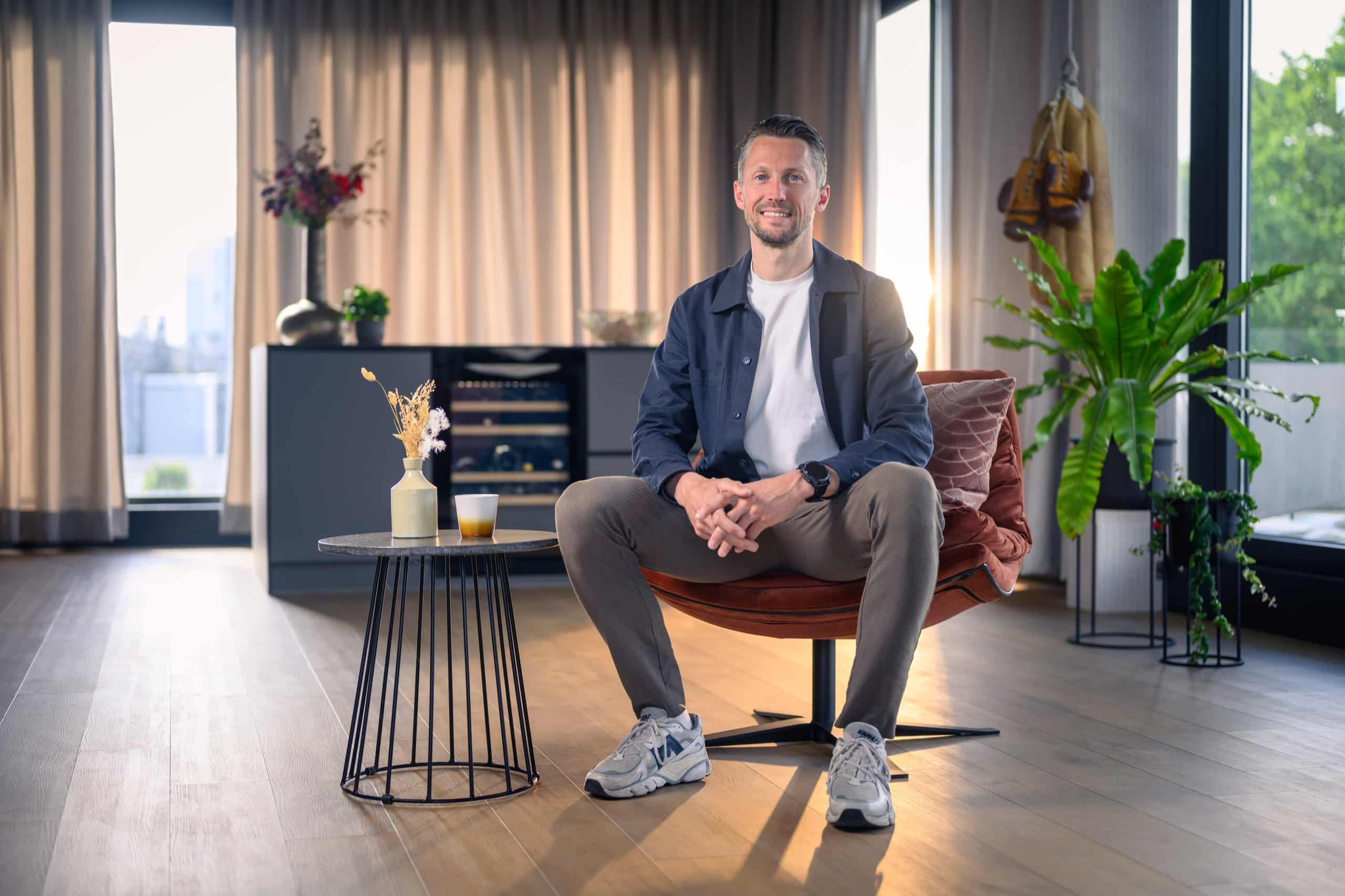 Professional in blauw colbert zit in een fauteuil in een lichte ruimte