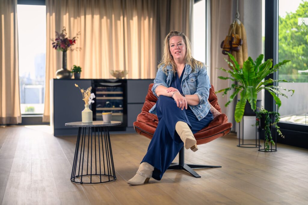 Vrouw zit ontspannen in een fauteuil in een lichte ruimte