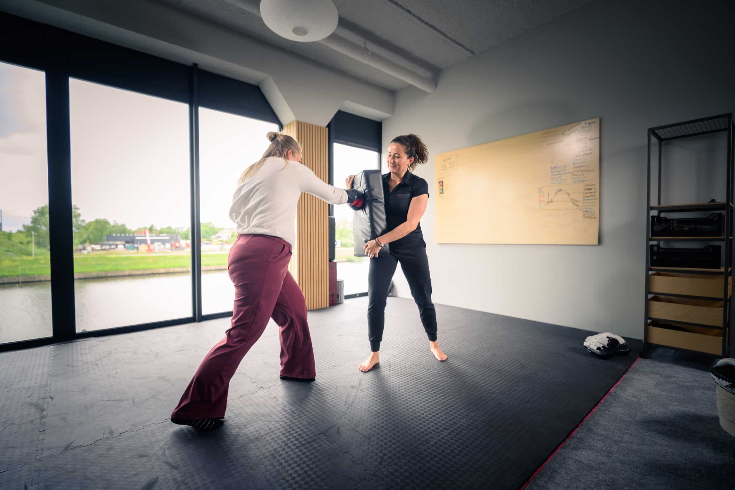 Deelnemer stoot op een stootkussen dat de coach vasthoudt in een studio