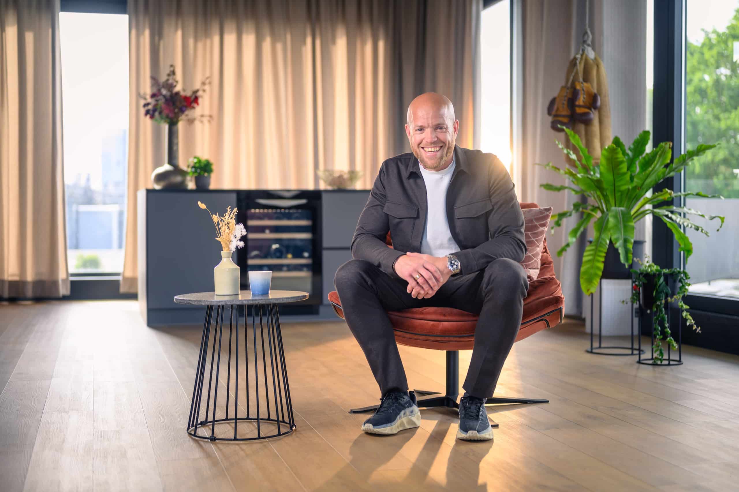 Leidinggevende in colbert zit ontspannen in een fauteuil in een lichte ruimte