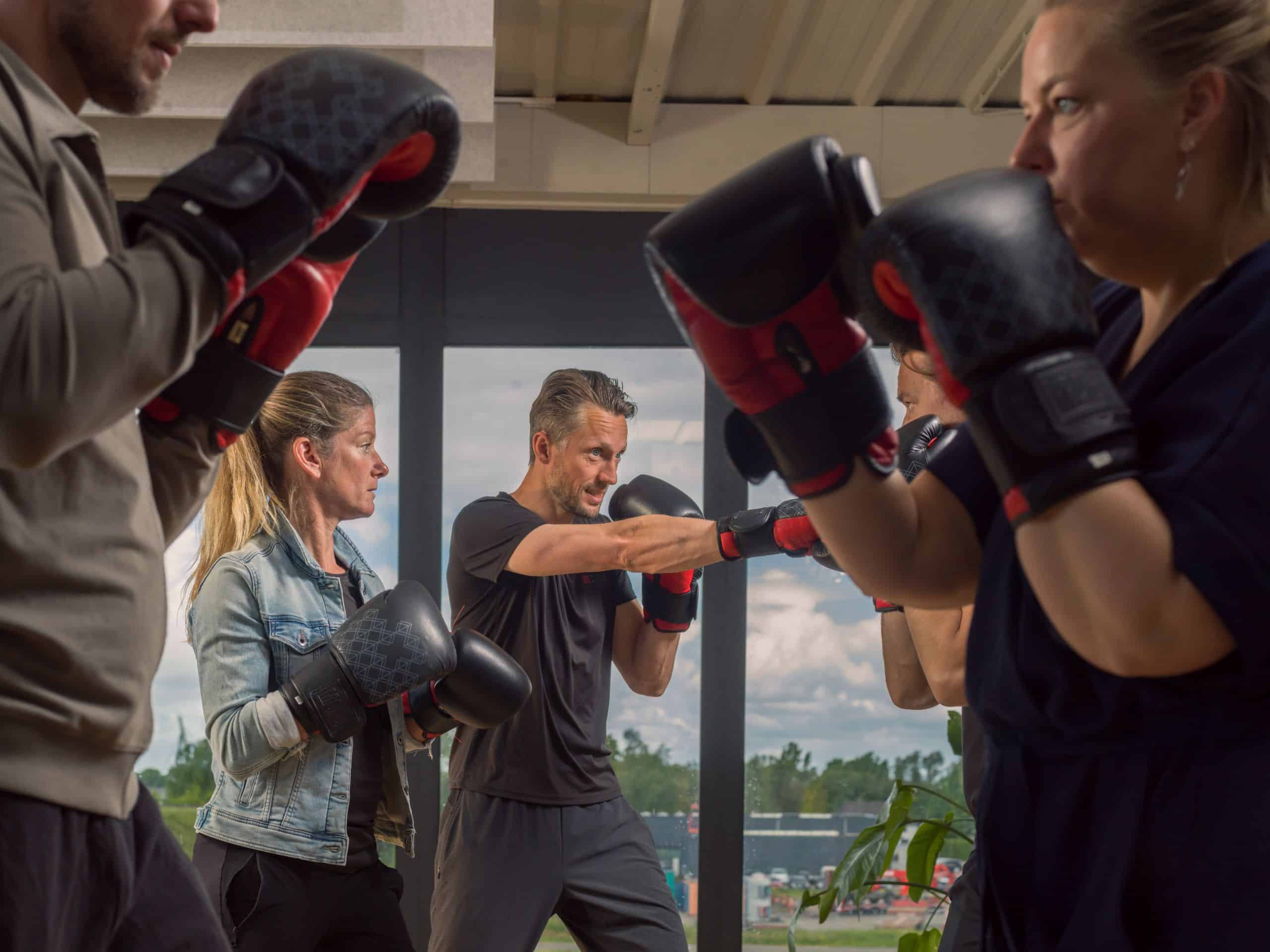 Deelnemers met bokshandschoenen trainen in een studio